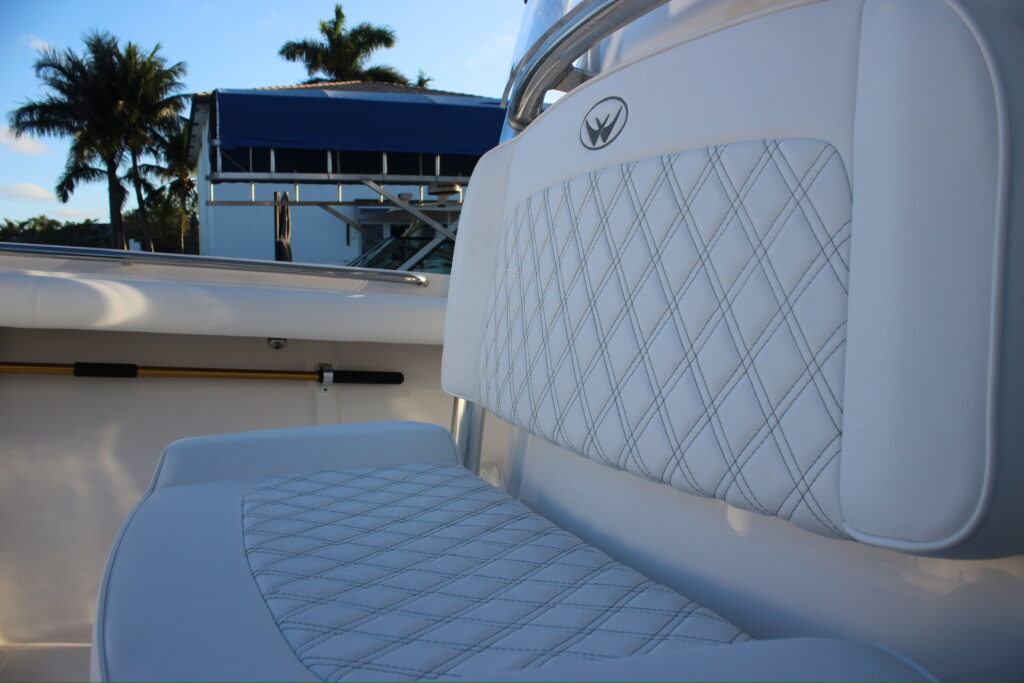 A white boat featuring a white seat and a white backrest, set against a calm water background.